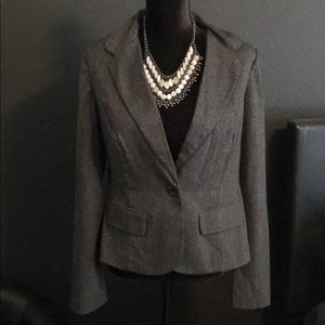 Gray women’s blazer with buttons in front.